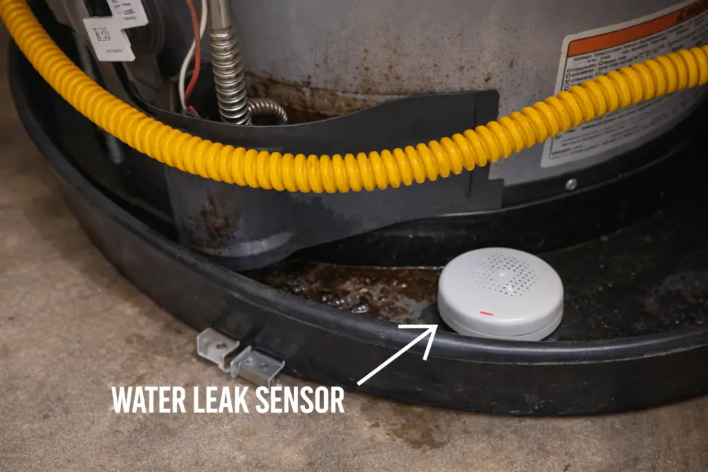 Water heater sitting in a drain pan with a leak detector nearby.