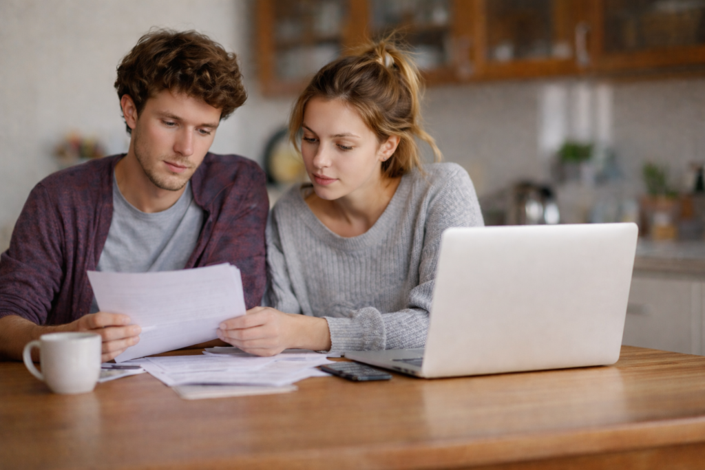 calm_repair_planning Homeowners reviewing household budget and home maintenance documents at a kitchen table while planning upcoming home repairs.